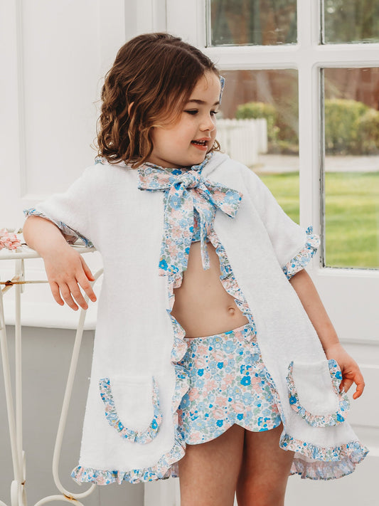 Hooded towelling poncho with blue floral ruffle trim and neck bow