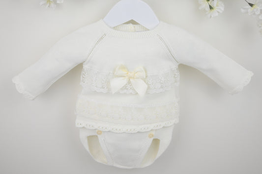 White baby romper with lace details and a bow on a white background