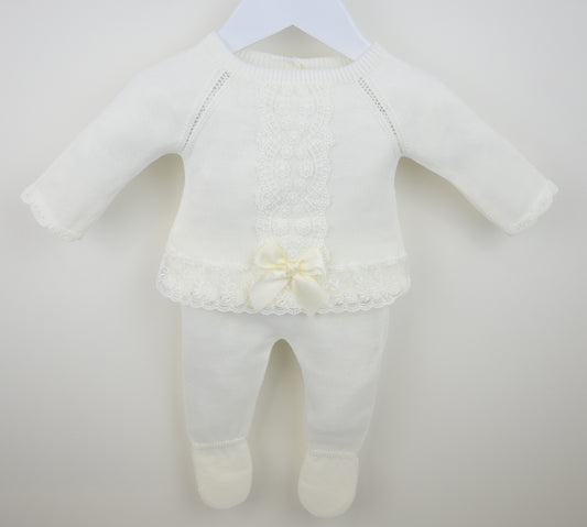 White baby outfit with a lace detail on a plain background