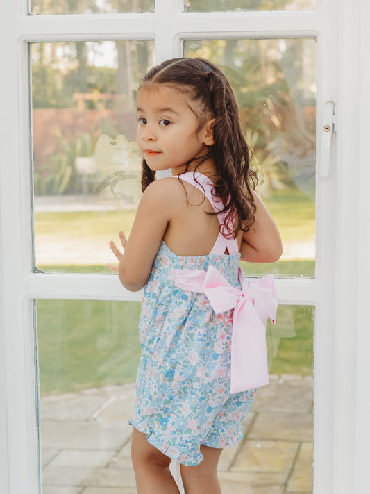 Floral playsuit with light blue print and pink bow detail at back, spaghetti straps