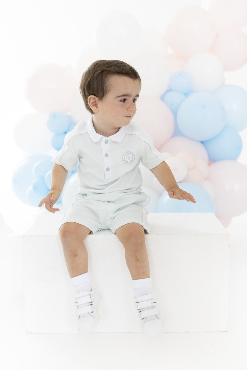 Child in a white outfit with balloons in the background