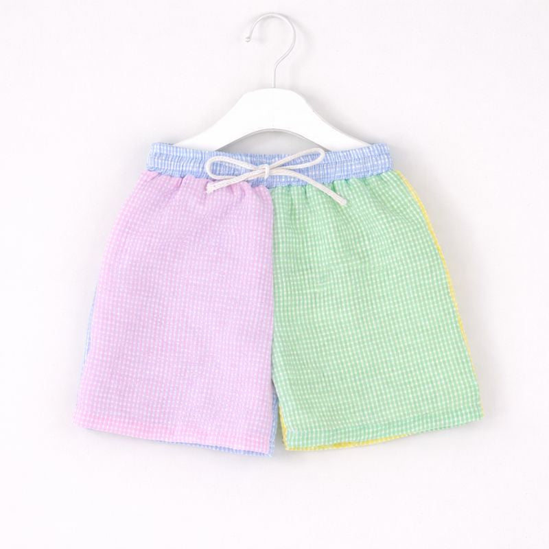 Two checkered aprons, one pink and one green, hanging on a white hanger against a white background.