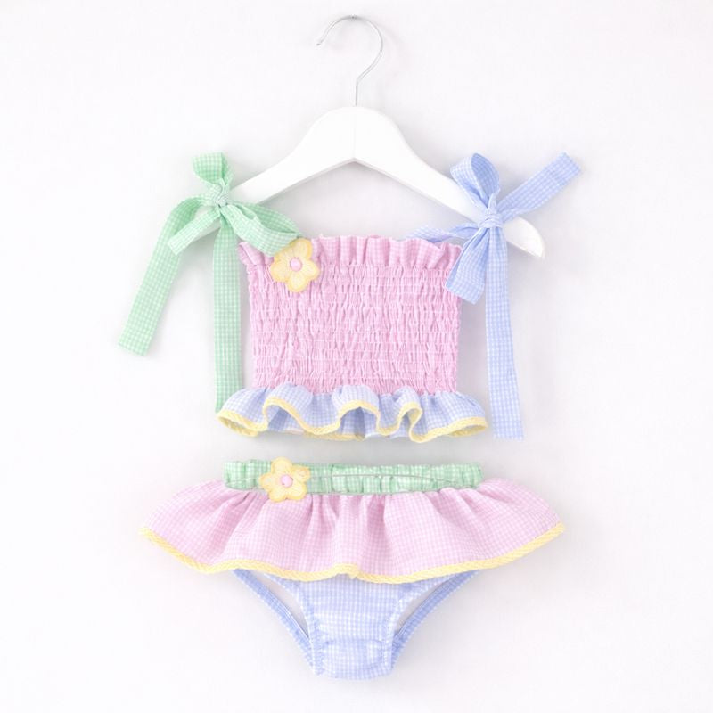 Pastel-colored baby swimsuit set with ruffles on a white background