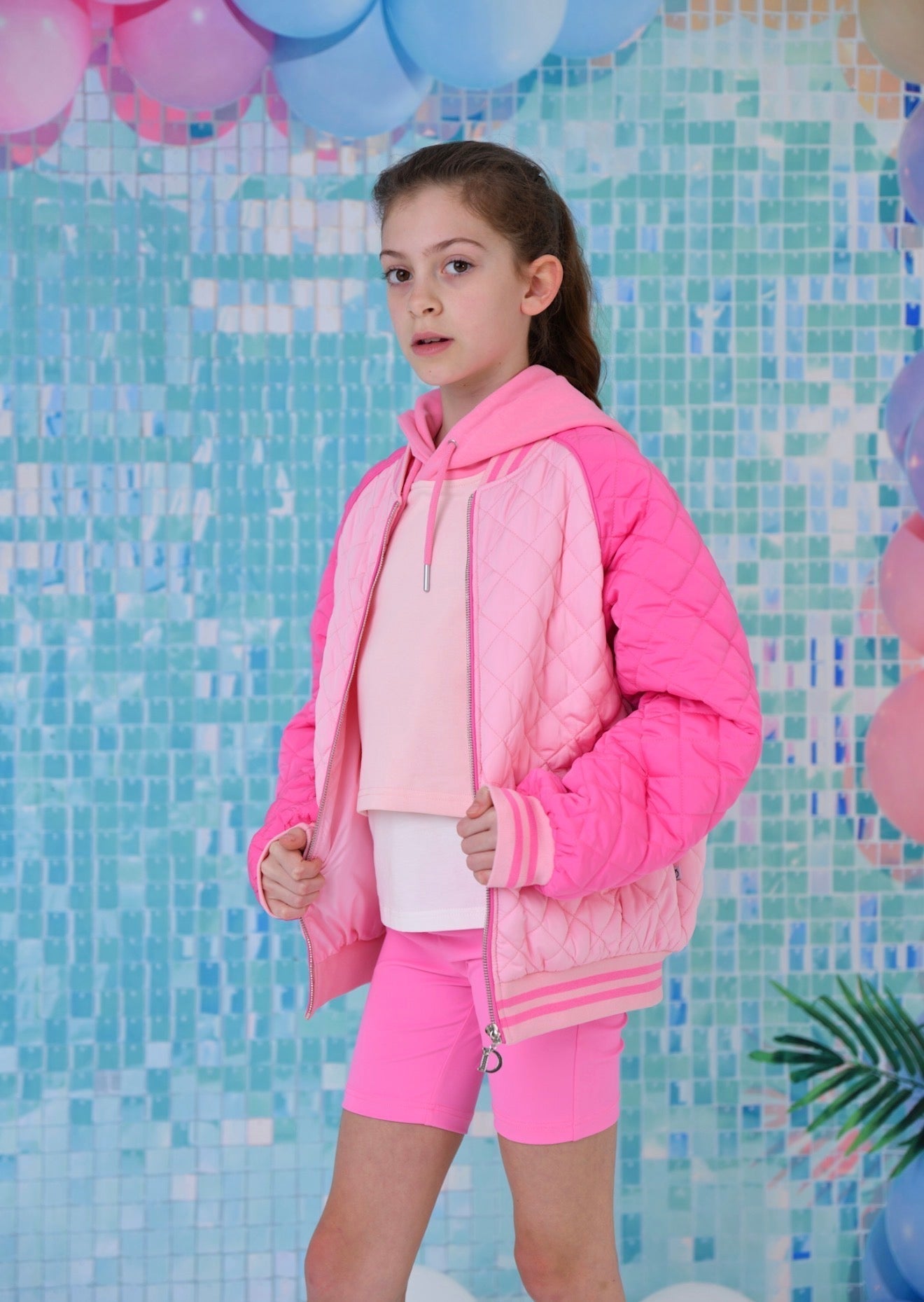 Bright pink kids quilted bomber jacket with zip and striped hem, front view
