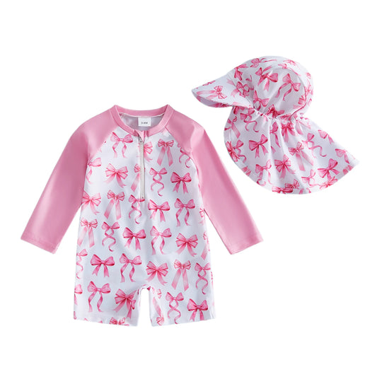 Baby swimsuit with pink bows and matching hat on a white background