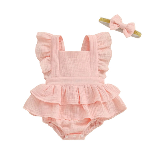 Pink baby romper with ruffles and matching headband on a beige background