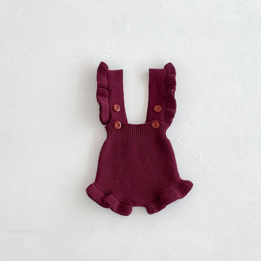 Burgundy baby knit romper close-up with ruffled arm openings and button straps