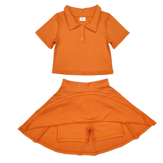 Orange children's shirt and skirt set on a textured white background