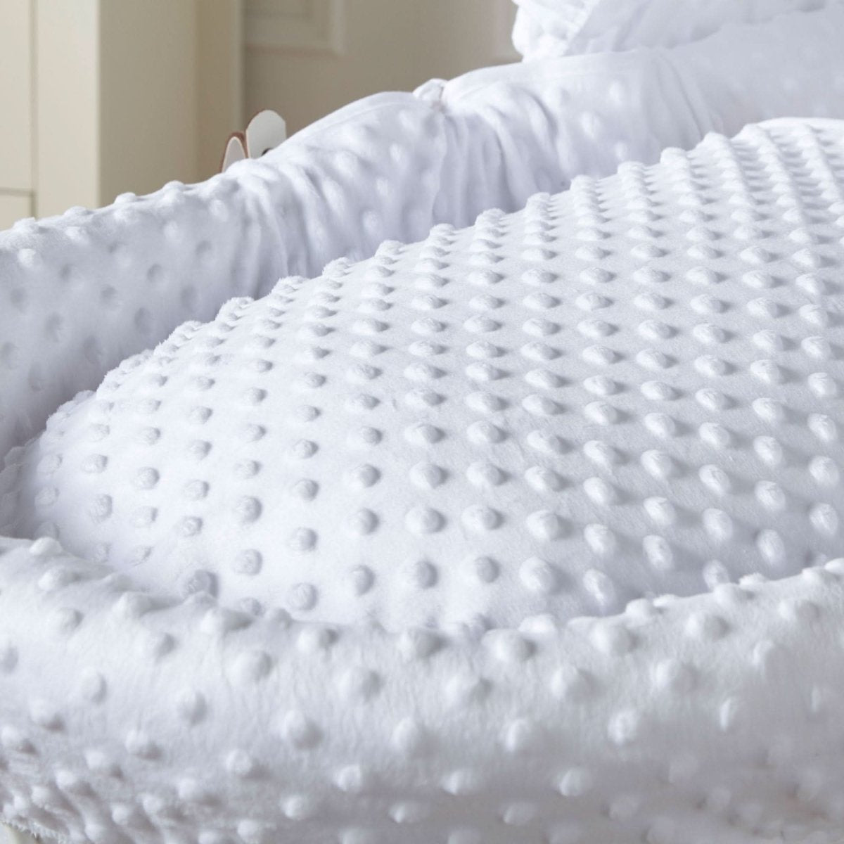 White textured padded mattress for Moses basket, close-up fabric dots