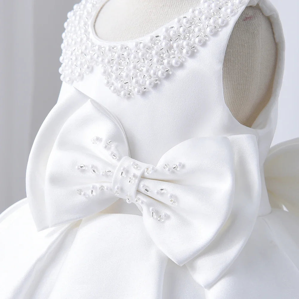Girls' white christening dress bodice close-up with beaded collar and satin bow