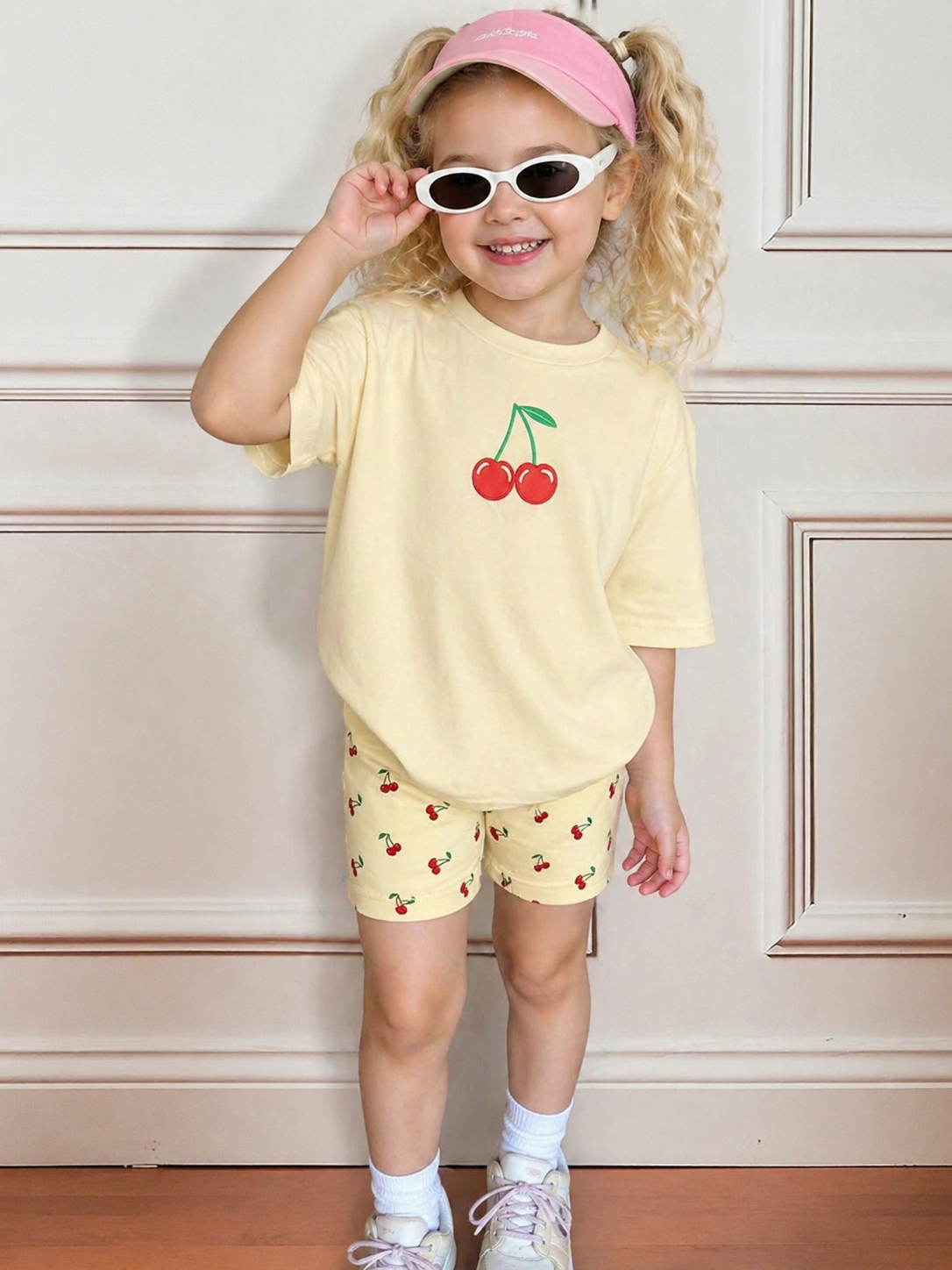 Girls cherry print summer short set: pale yellow T-shirt with cherry graphic, matching shorts.