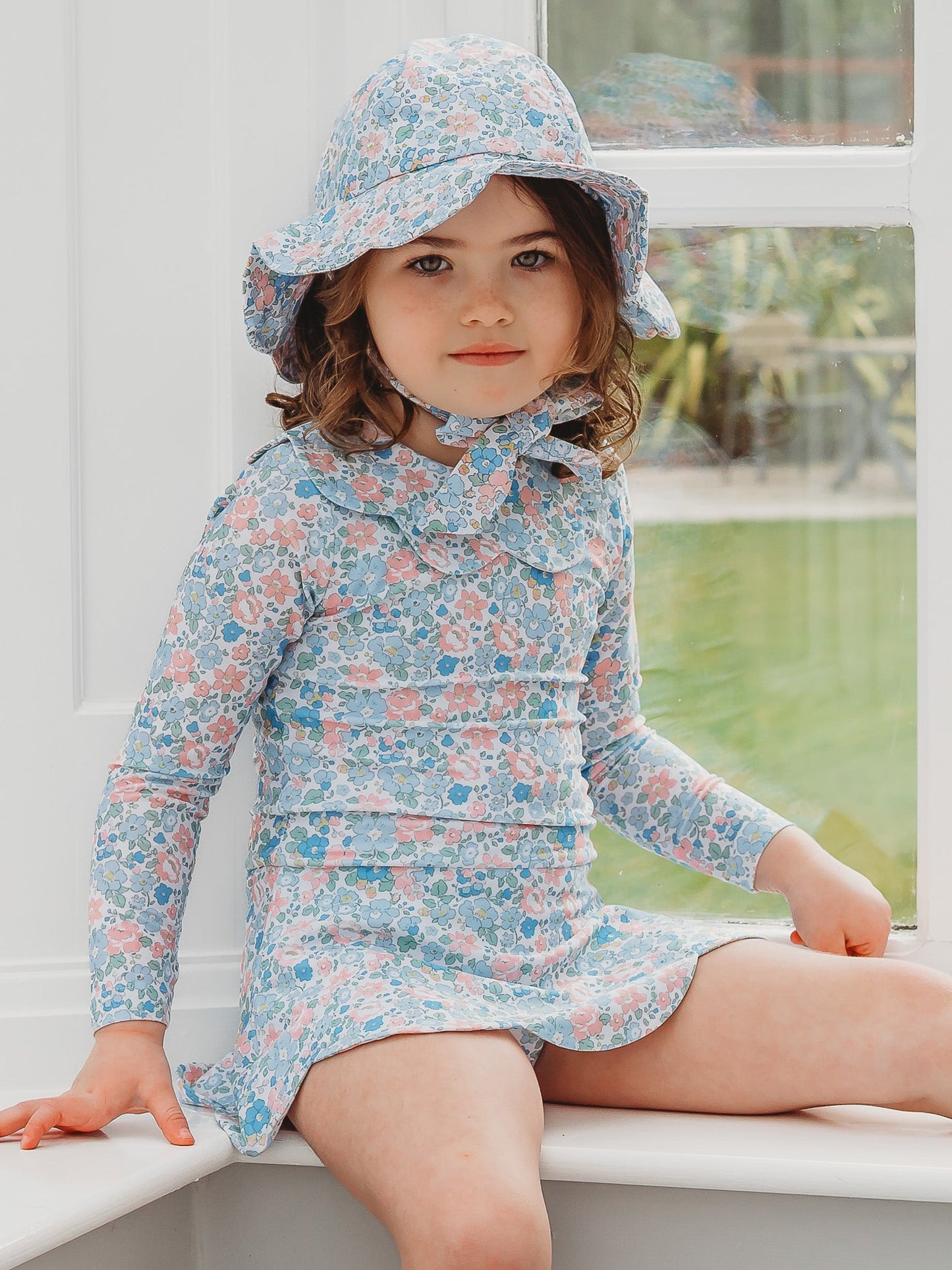 Floral light blue petal sunhat with wide brim and neck tie, worn