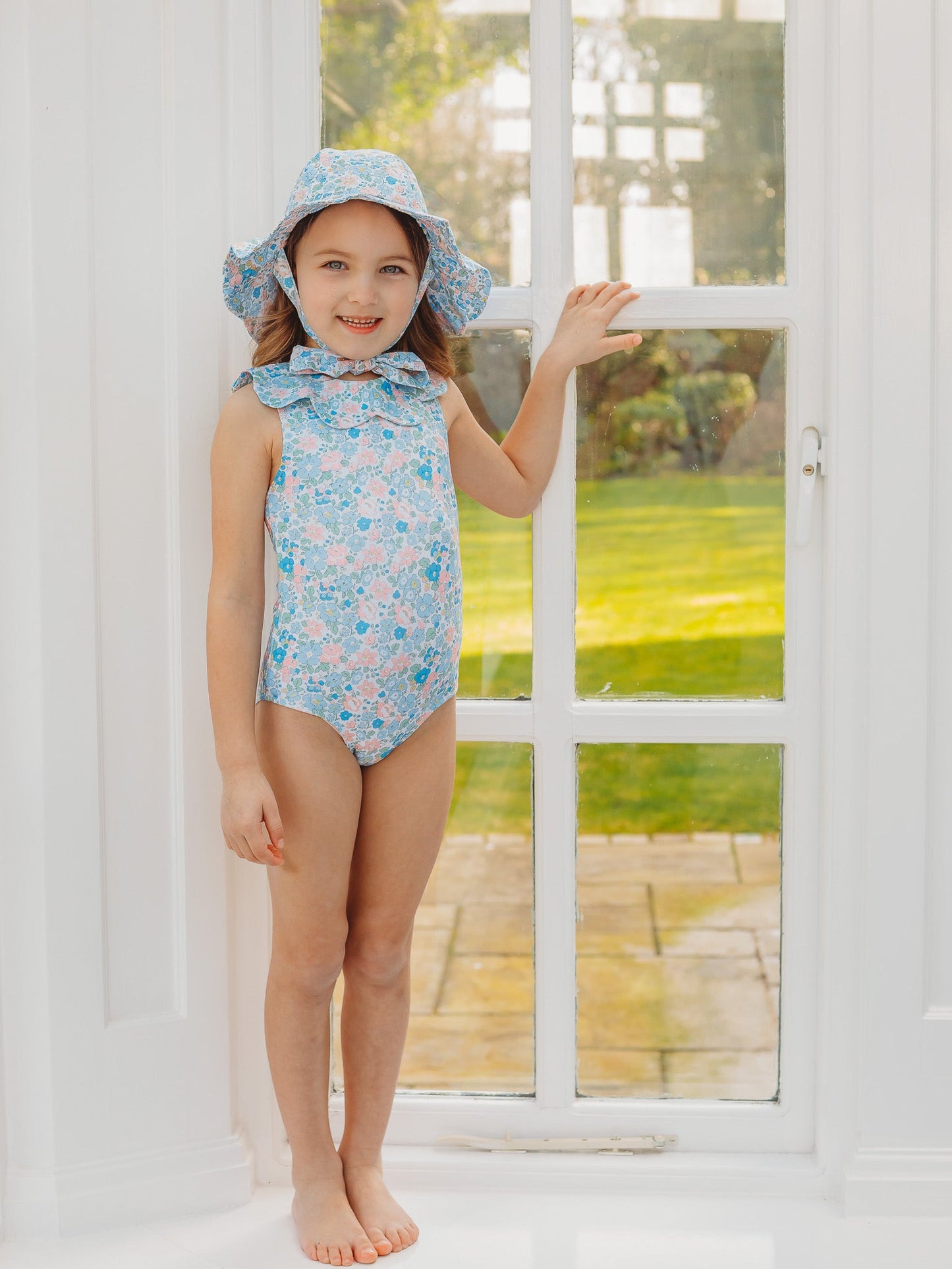 Light blue floral petal-collar sleeveless one-piece swimsuit, child waving