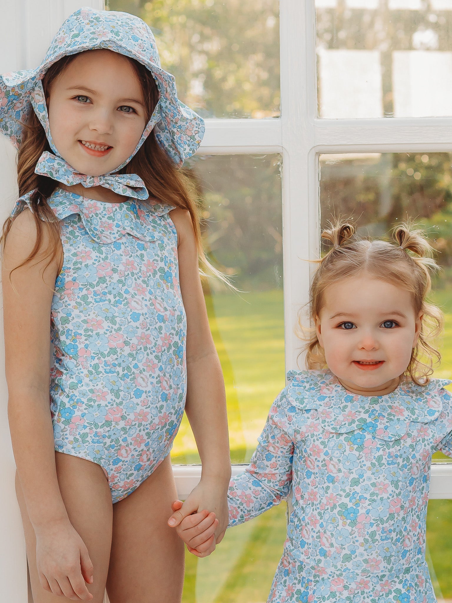 Light blue floral petal-collar sleeveless one-piece swimsuit on child, close view