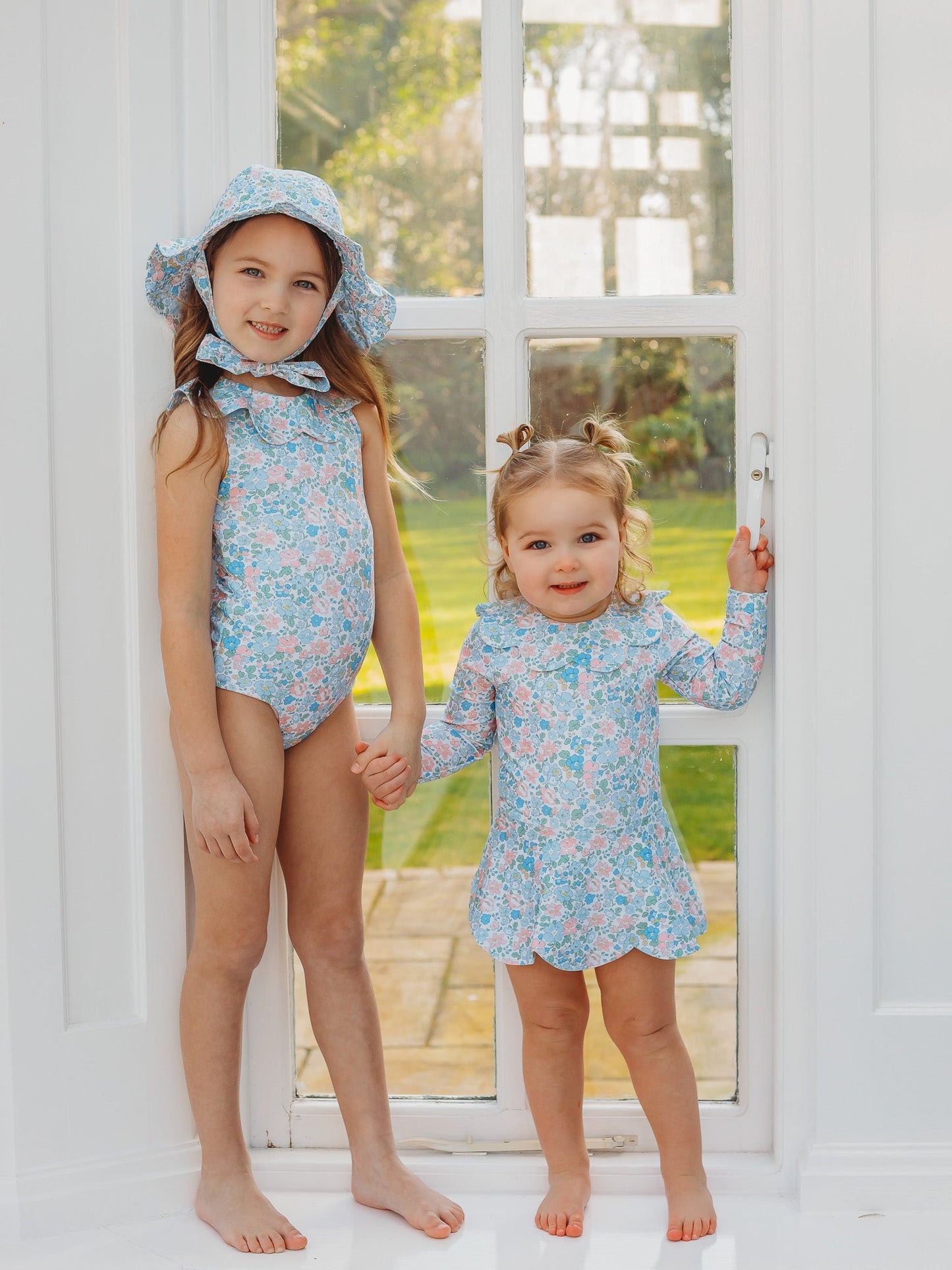Light blue floral petal-collar sleeveless one-piece swimsuit on two standing kids