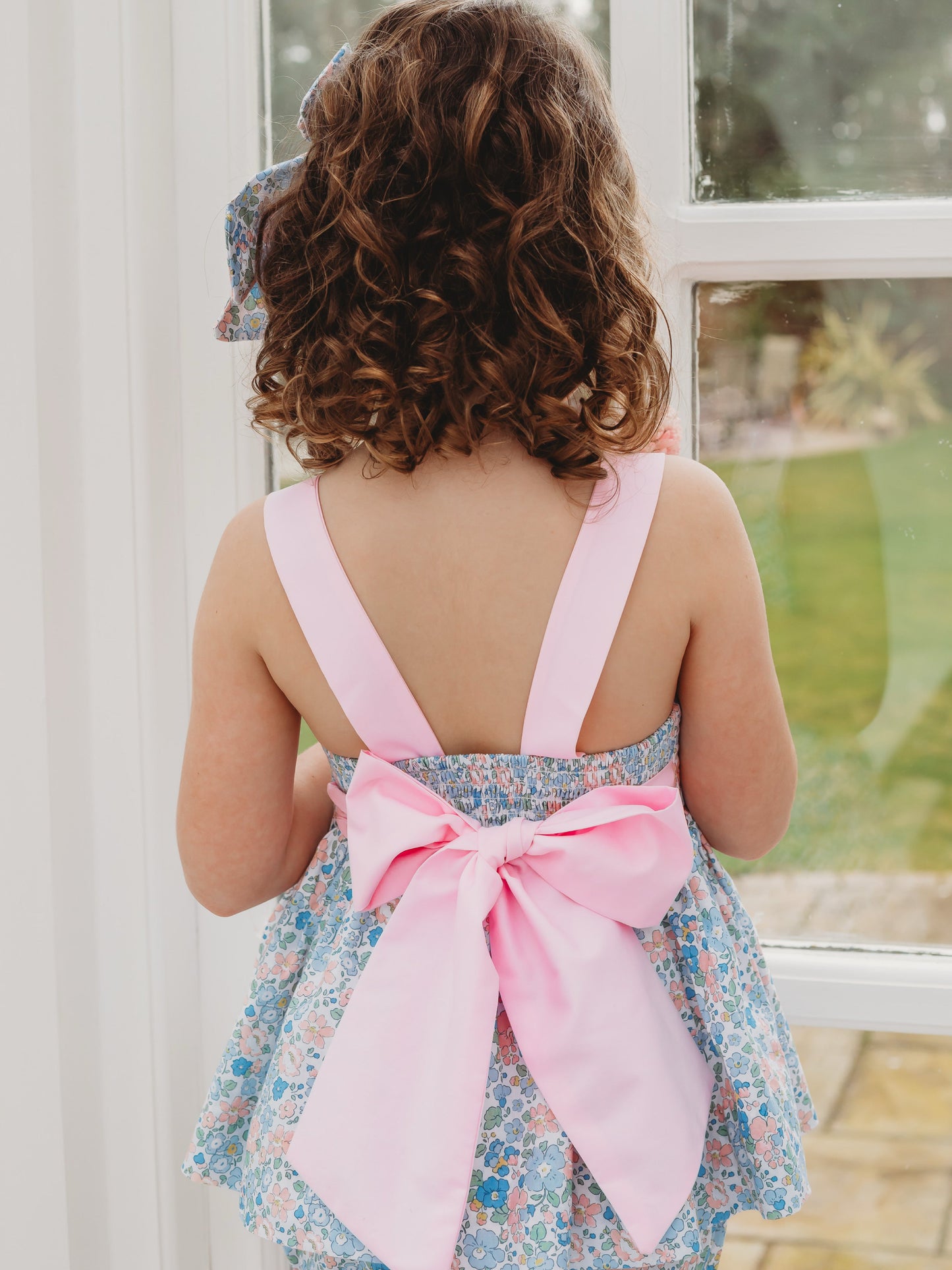 Back view of floral bow-back bloomer set with white straps and large pink bow