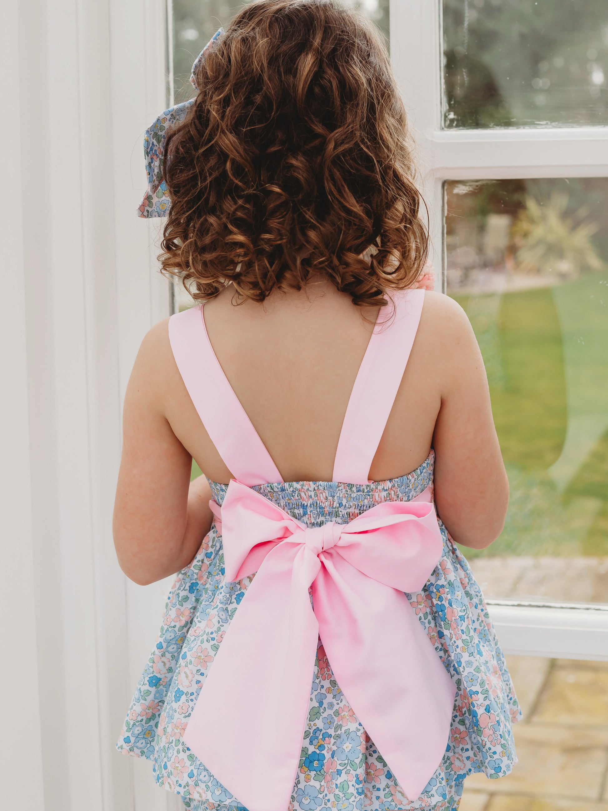 Back view of floral bow-back bloomer set with white straps and large pink bow