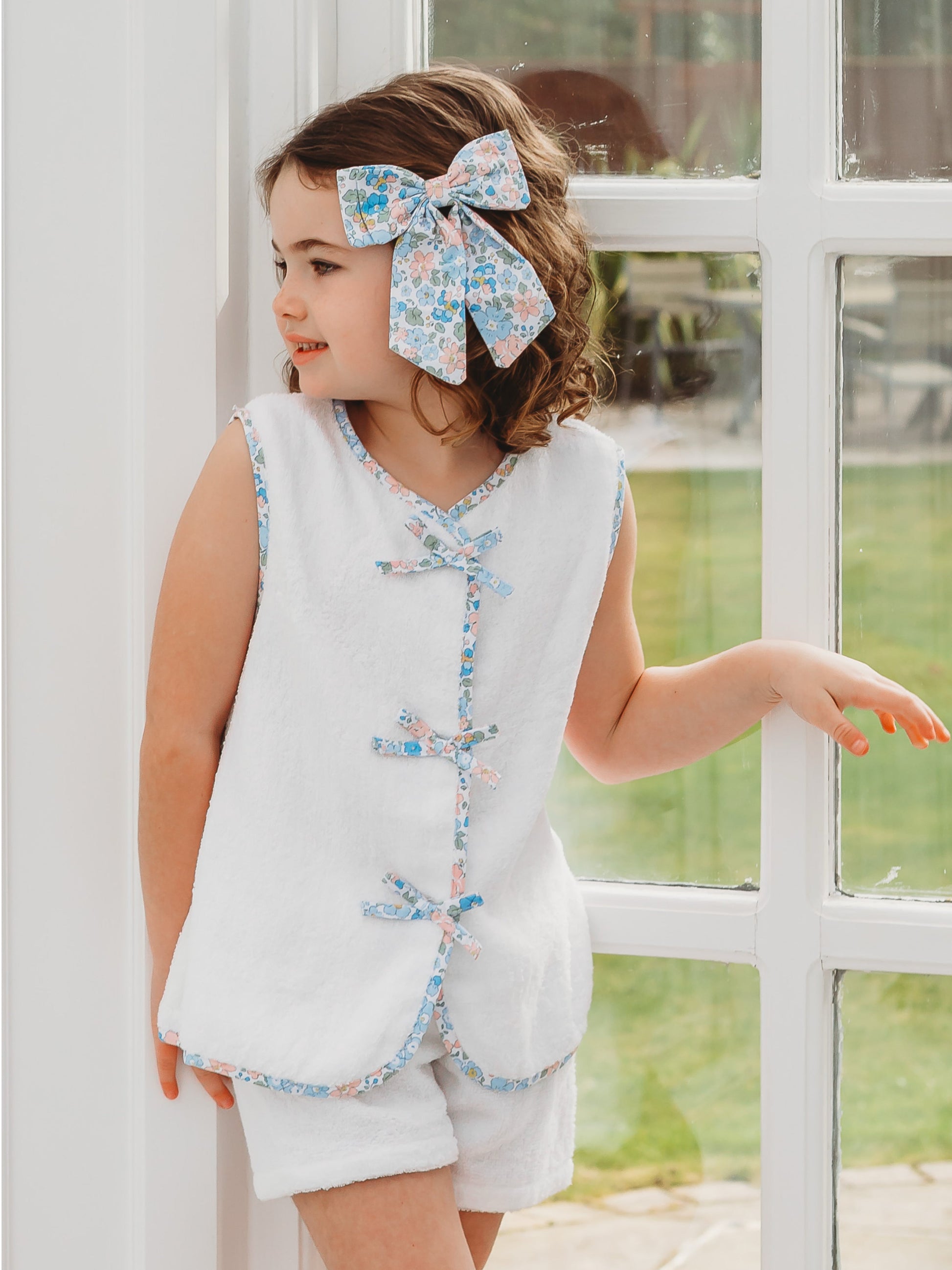 White towelling sleeveless top and shorts with blue floral trim and bow front detail