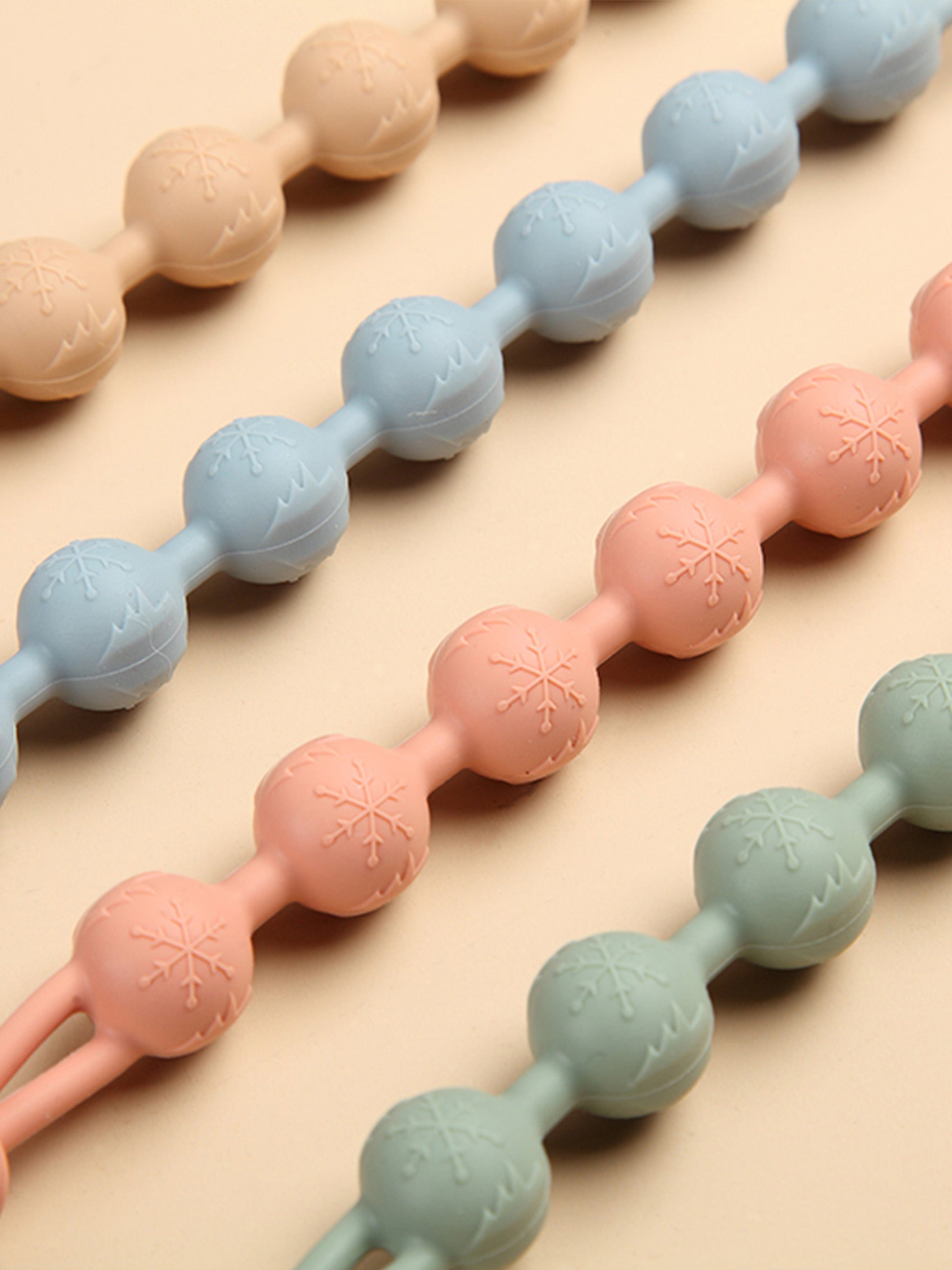 Close-up of pastel silicone bead teether segments with embossed snowflake pattern