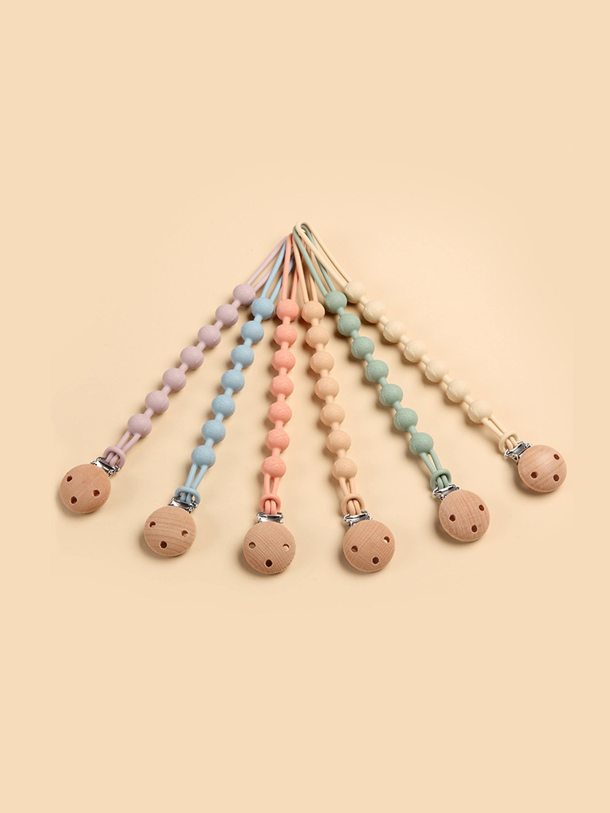 Pacifier clips and teethers in multiple pastel colors with round wooden ends