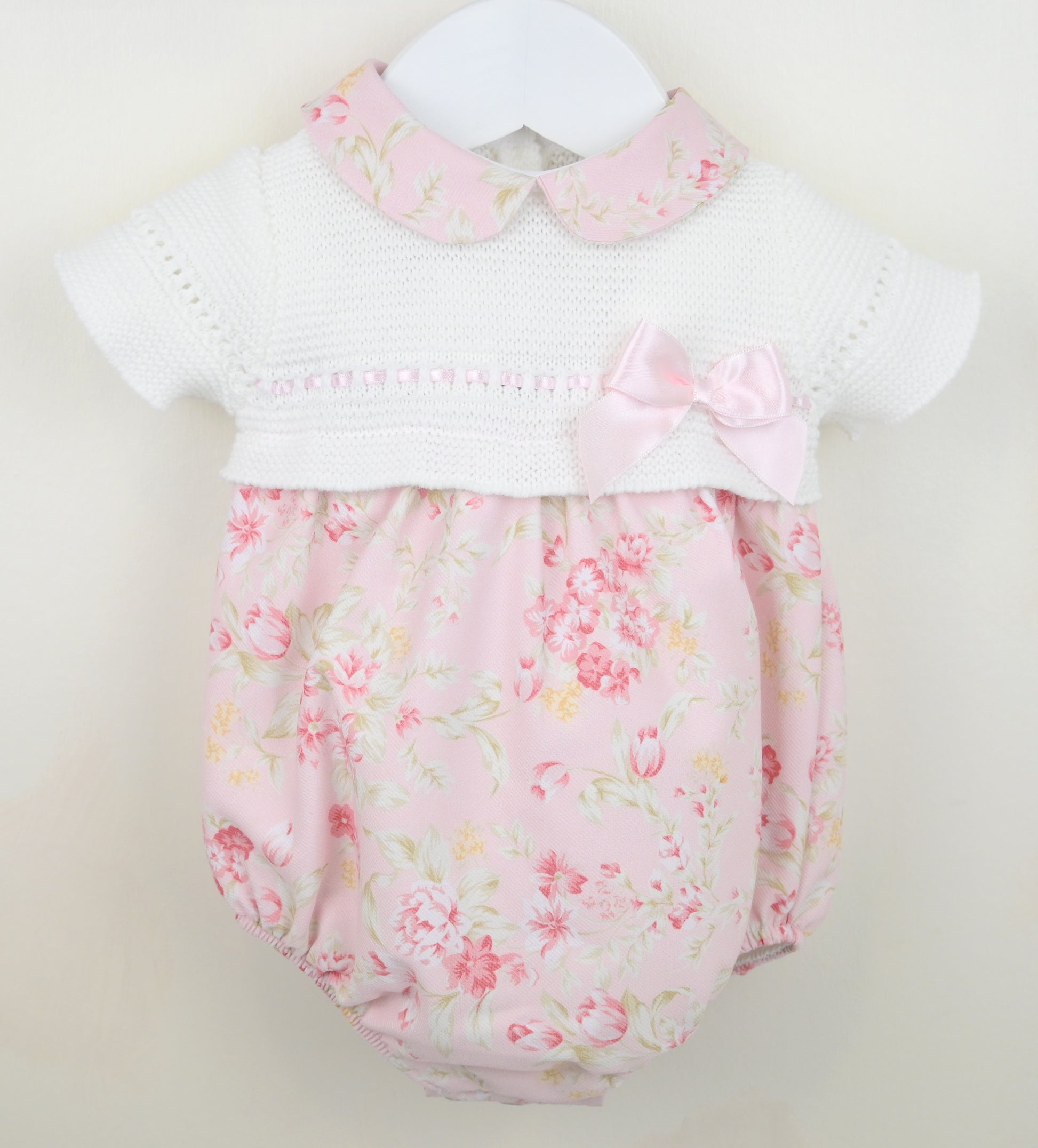 Baby romper with floral pattern and white collar on a light background