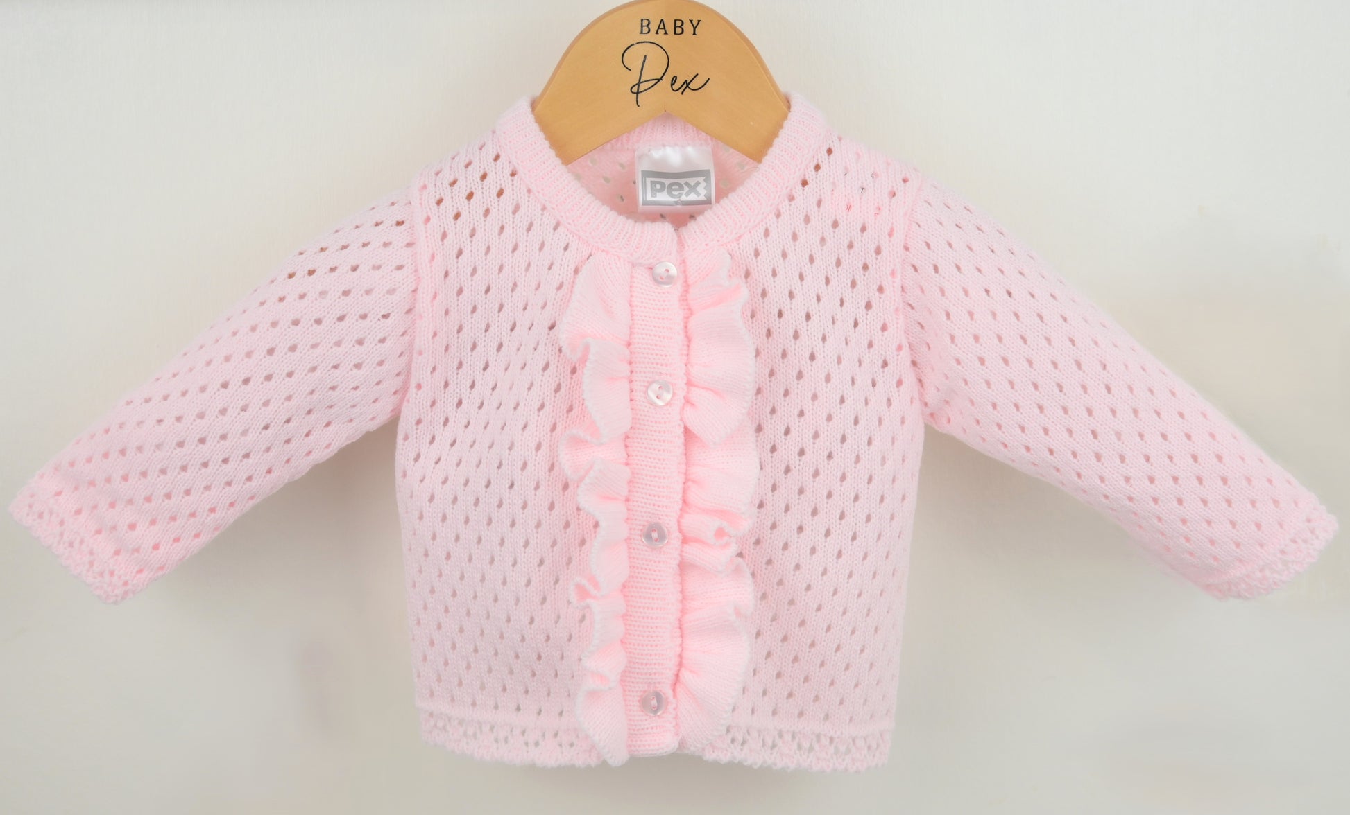 Pink baby cardigan on a hanger with a white background