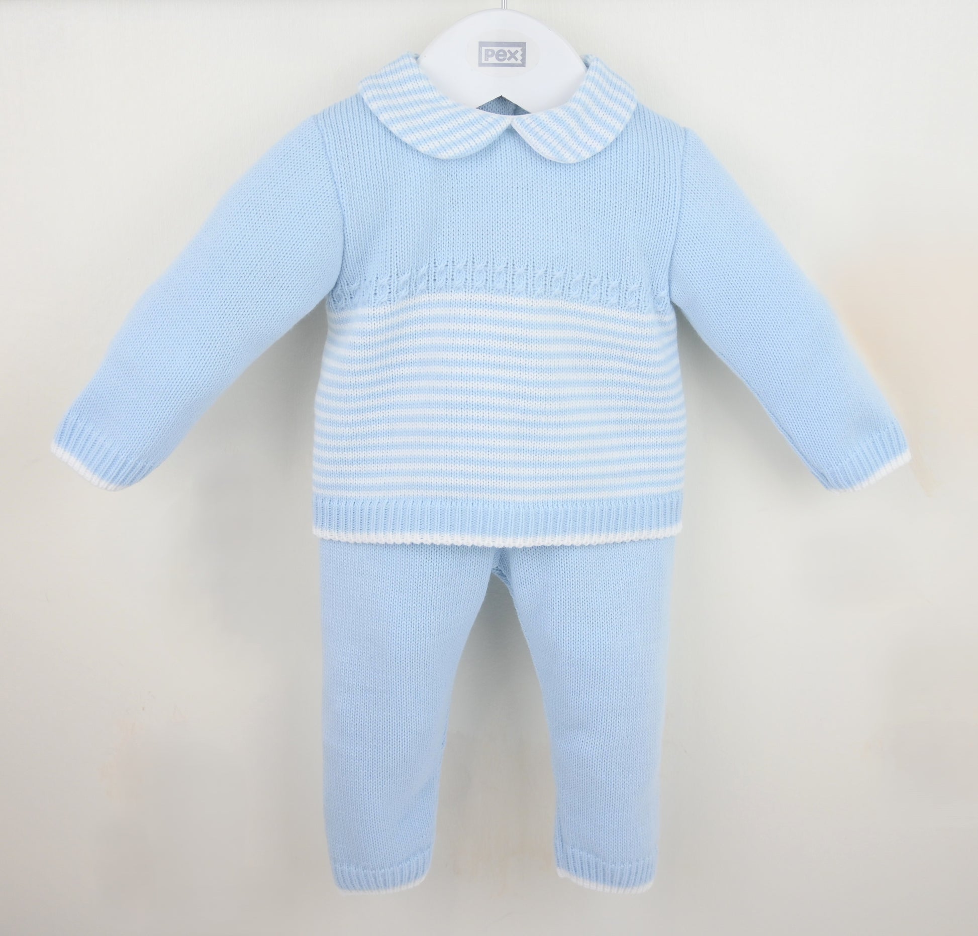 Light blue baby boys sweater and pants set on a beige background