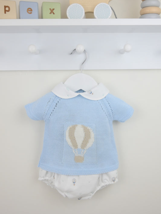Baby outfit with blue shirt and white diaper on a hanger against a neutral background