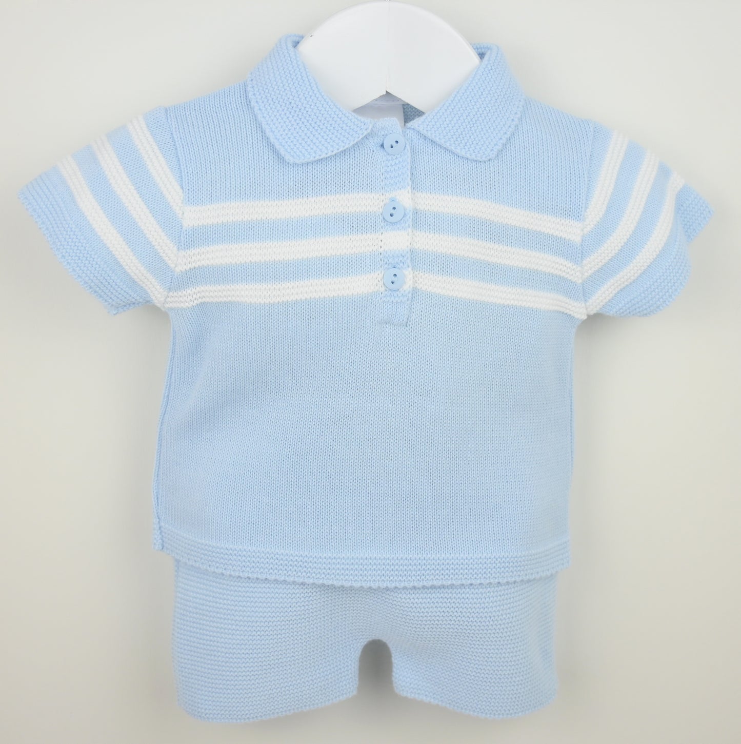 Light blue baby outfit with a polo shirt and shorts on a hanger against a light gray background