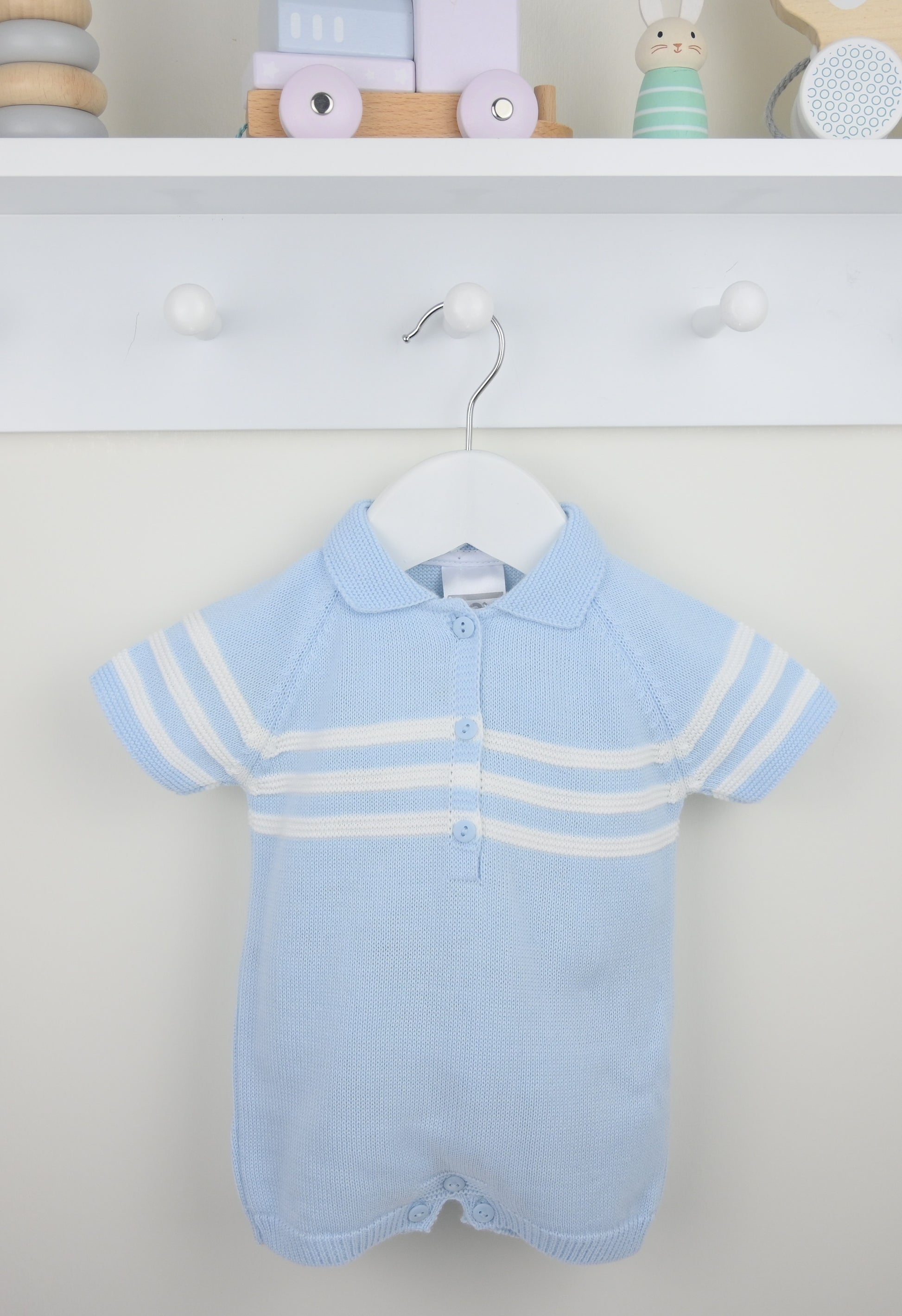Baby blue knitted romper with white stripes on a hanger against a neutral background.