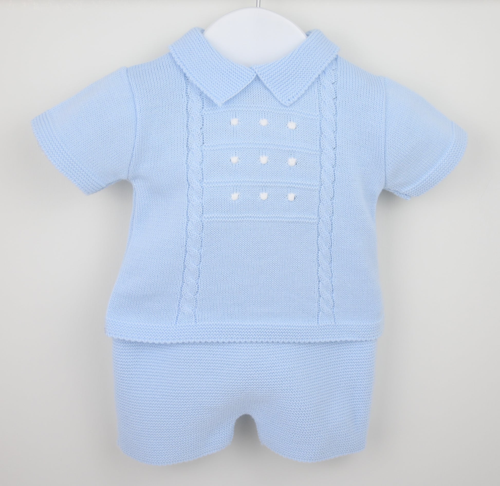Baby blue knitted shorts suit with collar and cable detail displayed on hanger