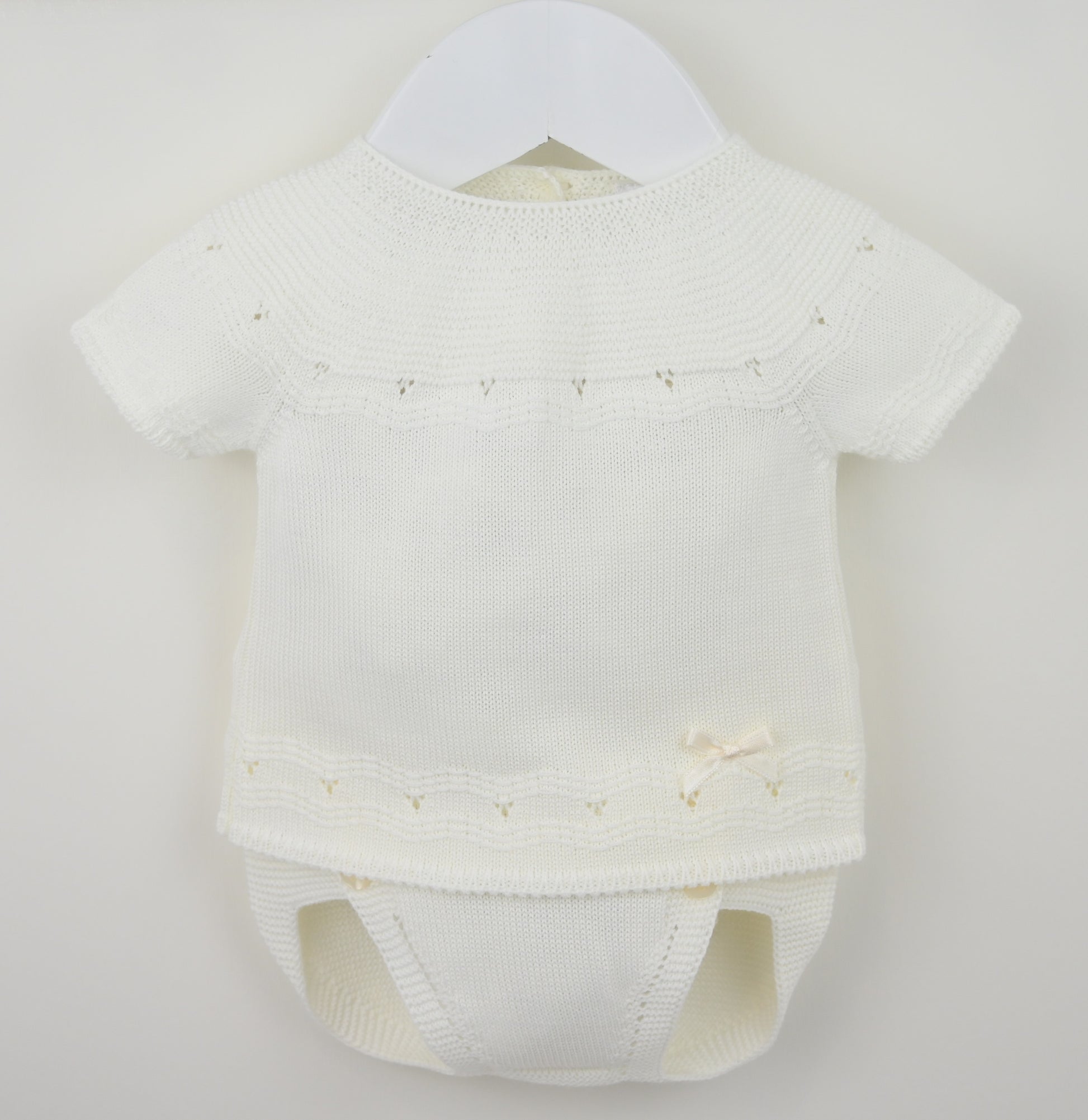 White baby romper with short sleeves on a hanger against a light gray background