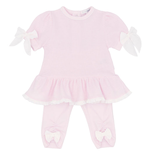 Pink baby dress with white ruffles on a white background