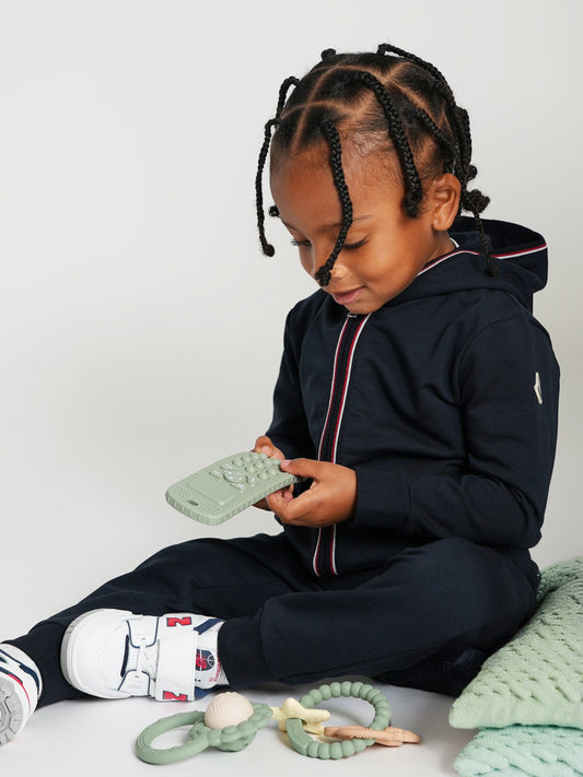 Pink phone-shaped teether in baby’s hands, silicone bumps for chewing