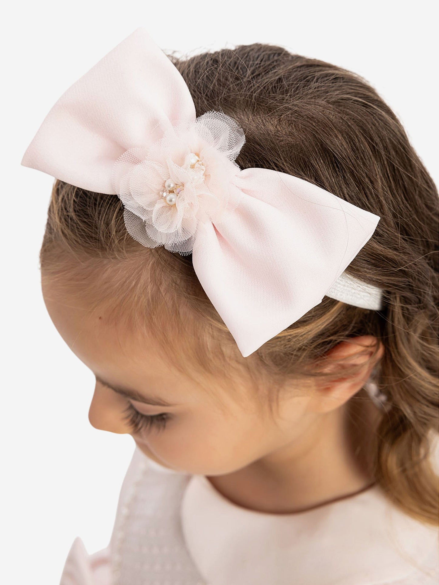 Pale pink tulle flower headband with wide bow on baby girl's hair