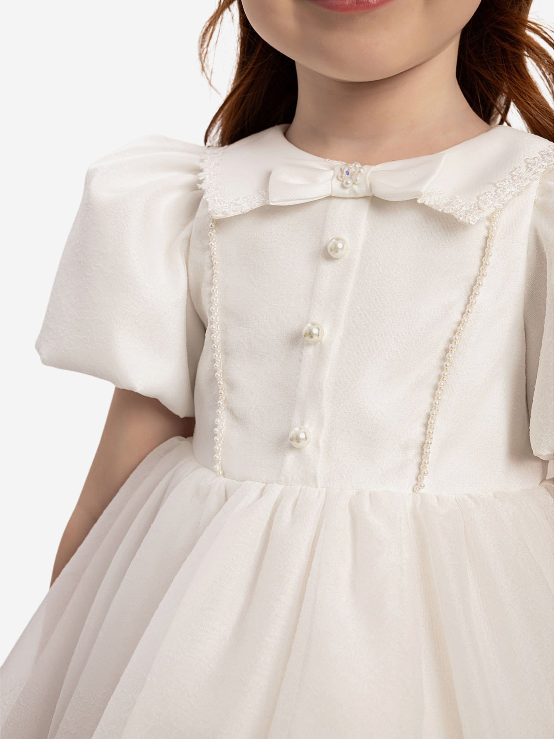 White collar dress close-up with pearl button details and textured trim
