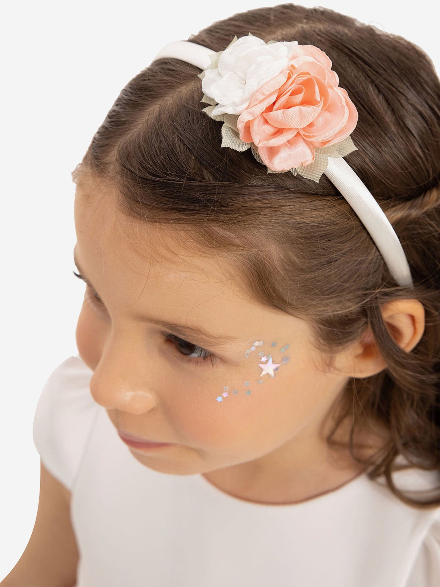 White headband with large peach and cream flower in child’s hair