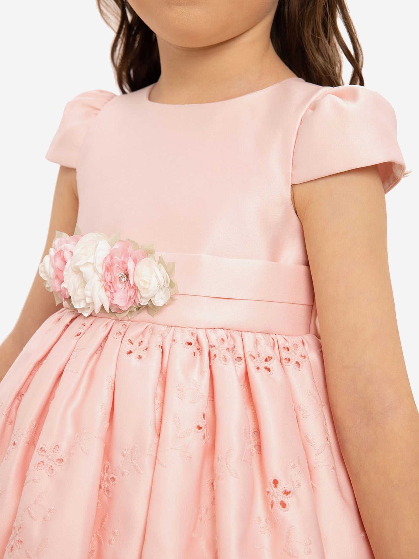 Pink dress close-up: floral waist applique, bow ribbon belt, textured skirt
