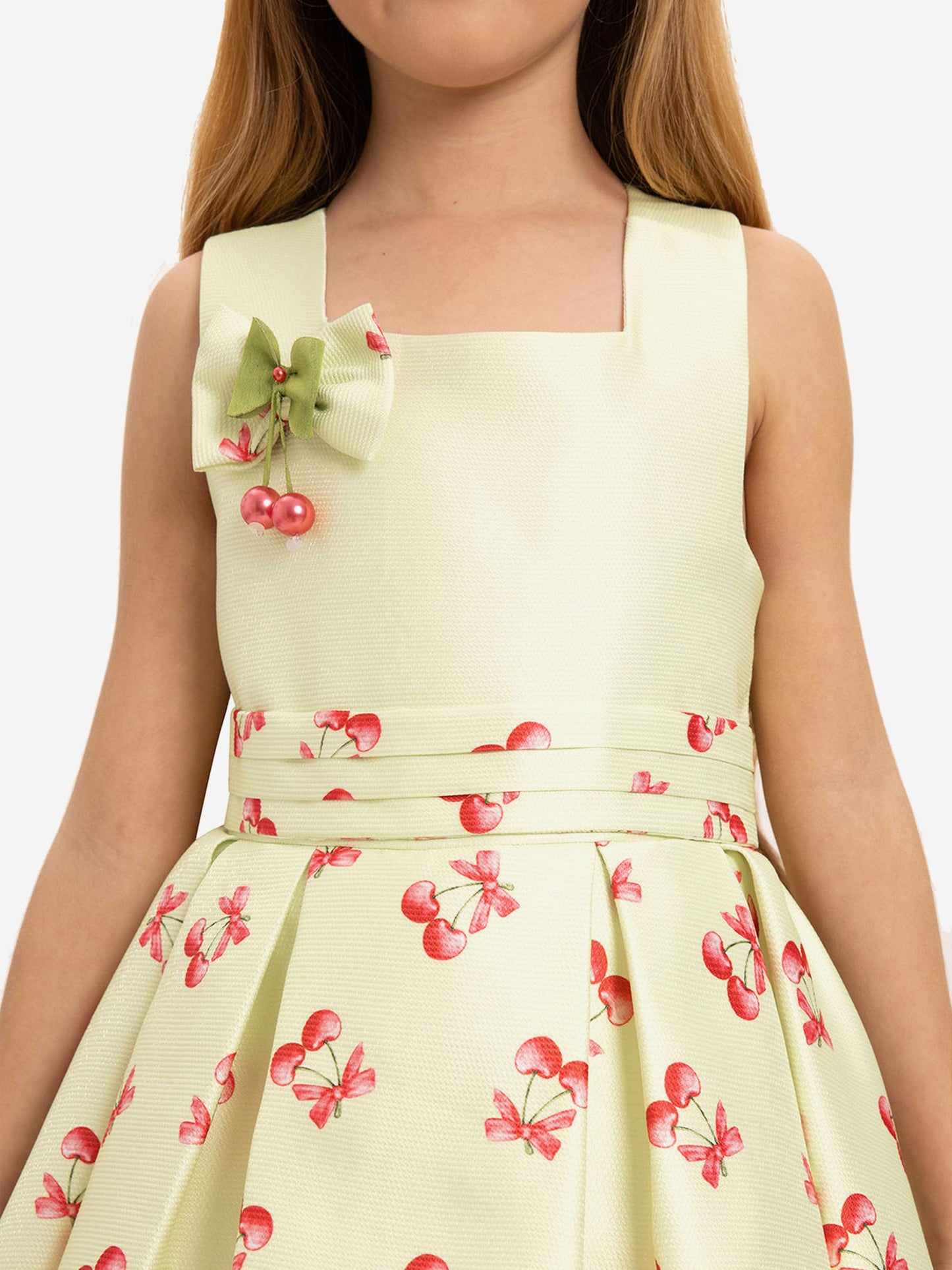 Close-up of pale green sleeveless dress with cherry print and fabric bow detail
