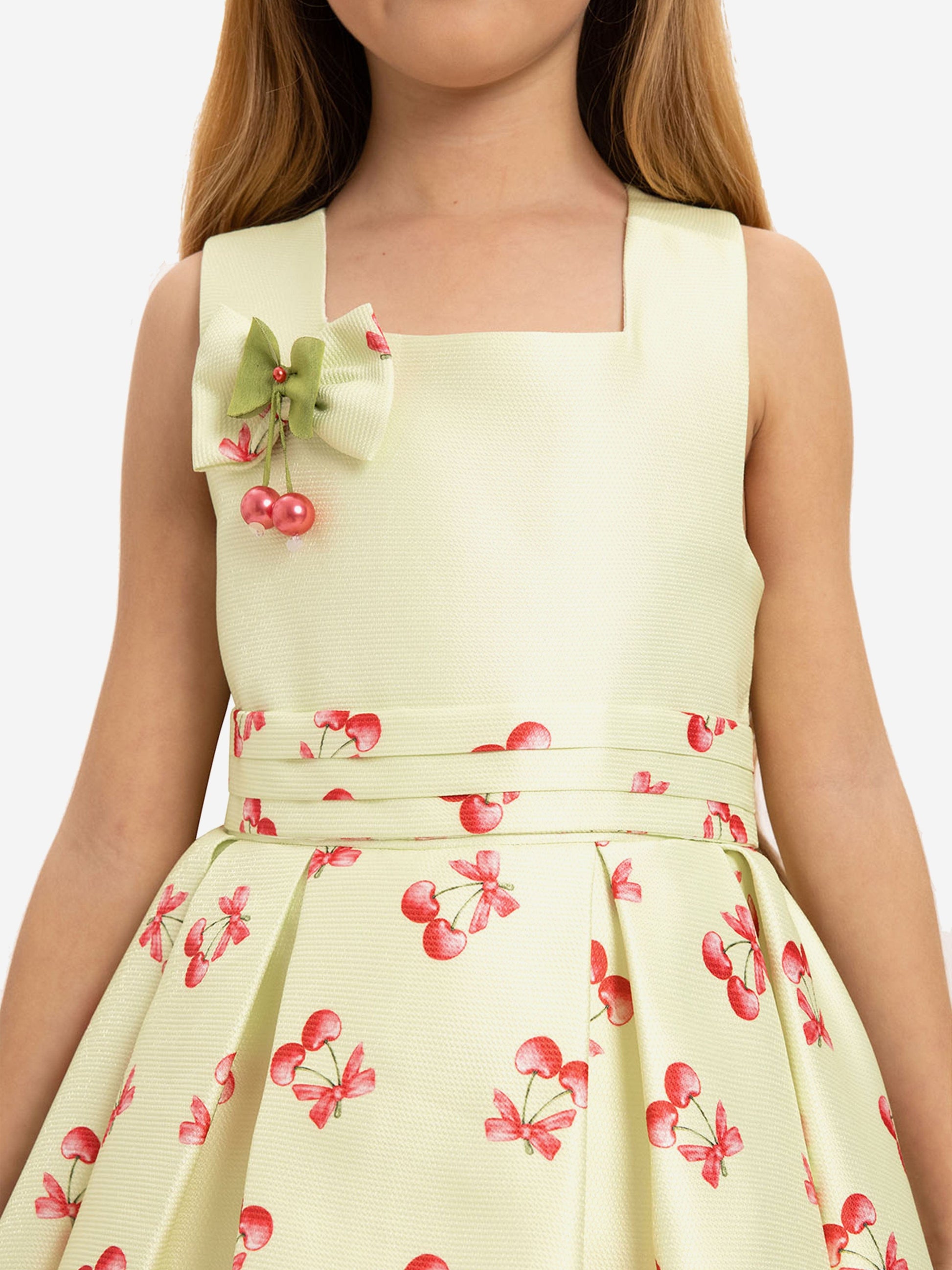 Close-up of pale green sleeveless dress with cherry print and fabric bow detail