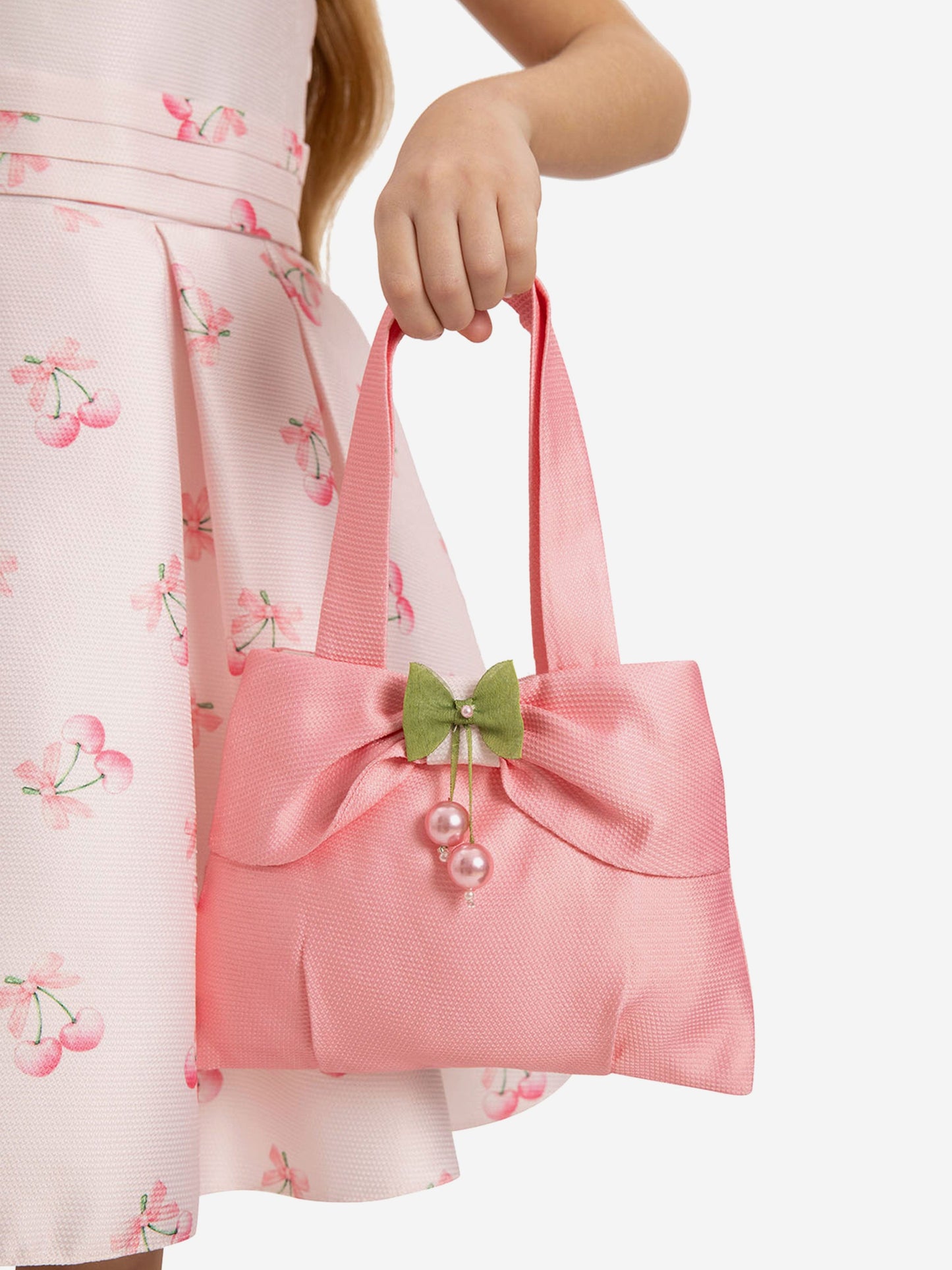 Pink matching tote bag with green bow and faux pearl cherry charm, held by hand