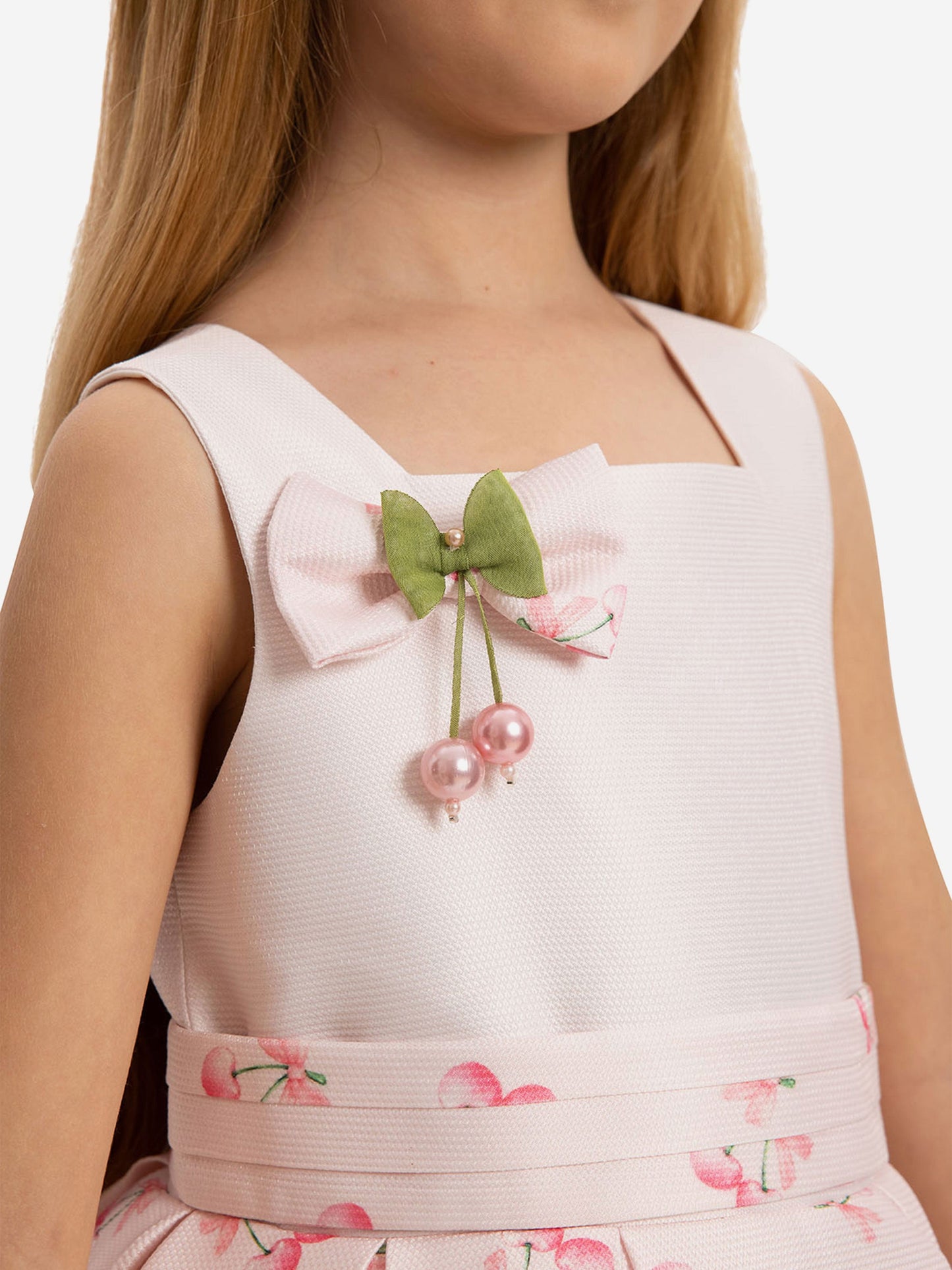 Pink cherry dress close-up: square neckline with green bow and faux pearl cherry charm