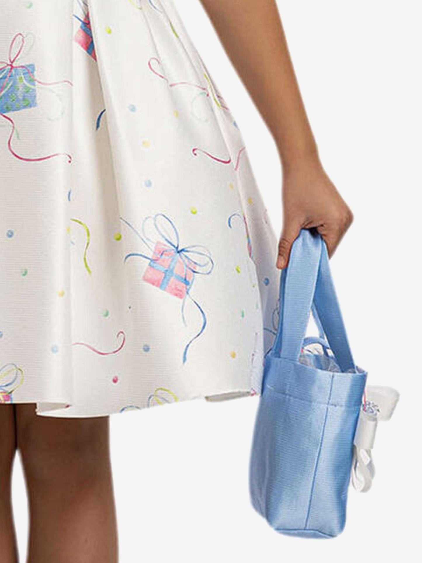 Close-up of light cream skirt with colorful gift pattern, plus light blue mini bag