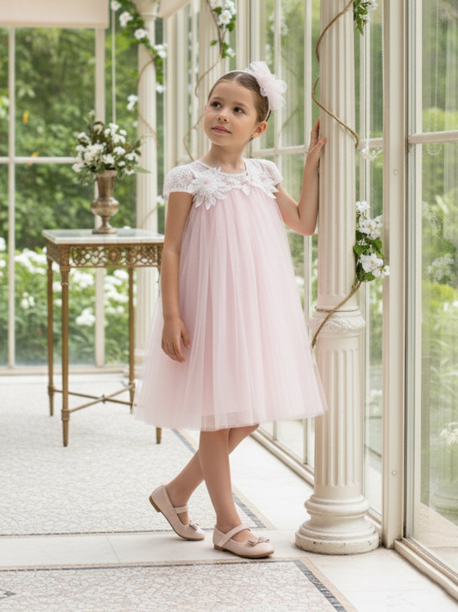 Pink tulle occasion dress with floral neckline and cap sleeves, wearing headband
