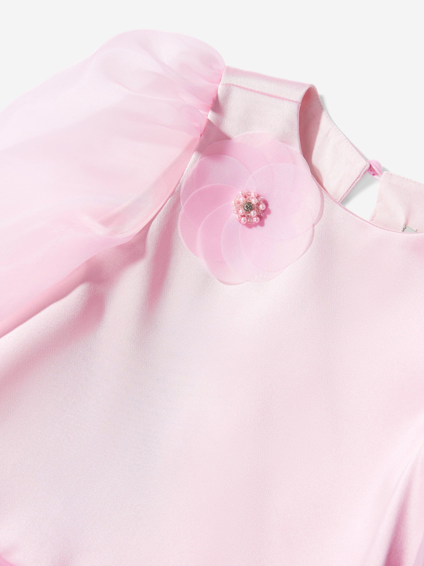 Pink dress bodice close-up with flower appliqué and sheer tulle sleeve