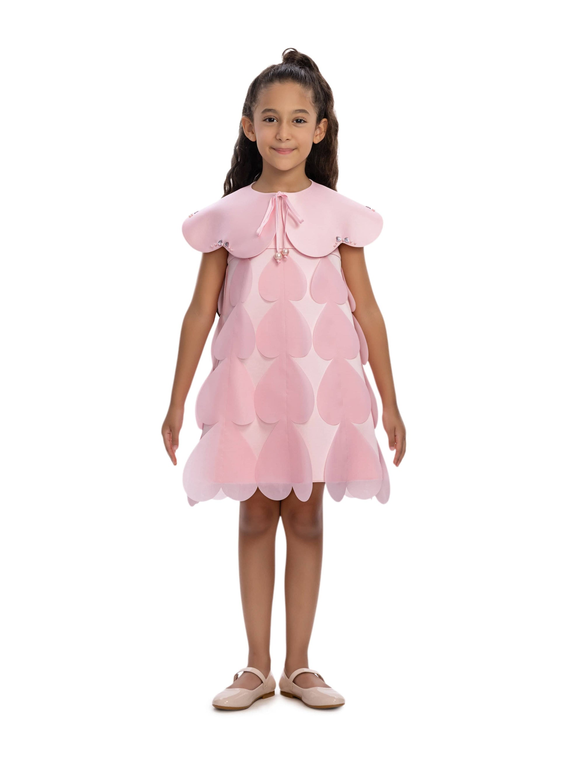 Pink heart-printed occasion dress with matching cape worn by a girl