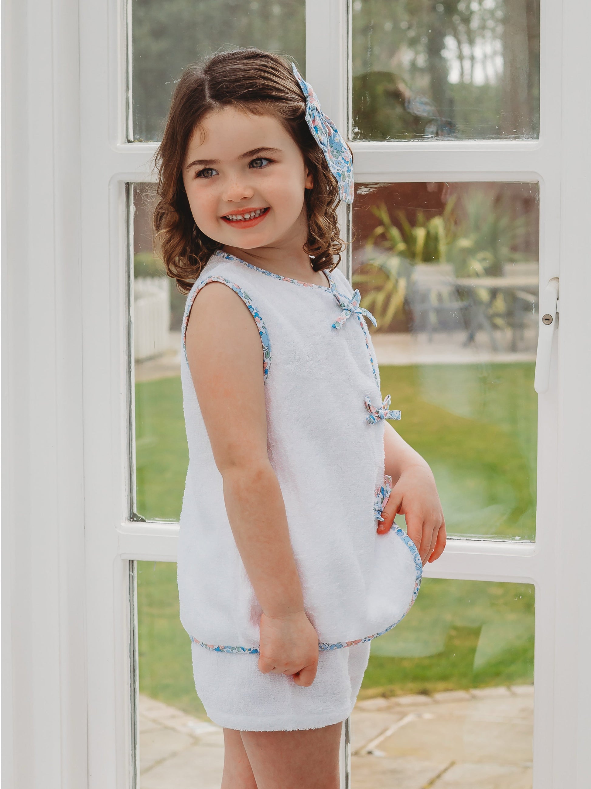 White towelling short set with blue floral trim; matching shorts and bow headband