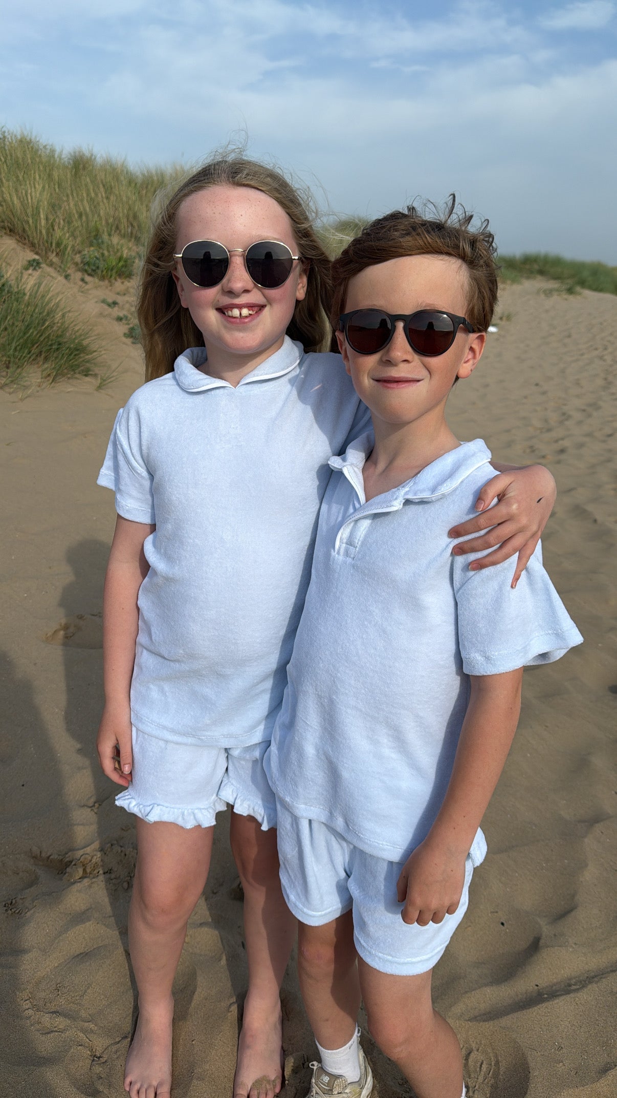 Blue towelling short set on two kids: polo collar tops and matching shorts