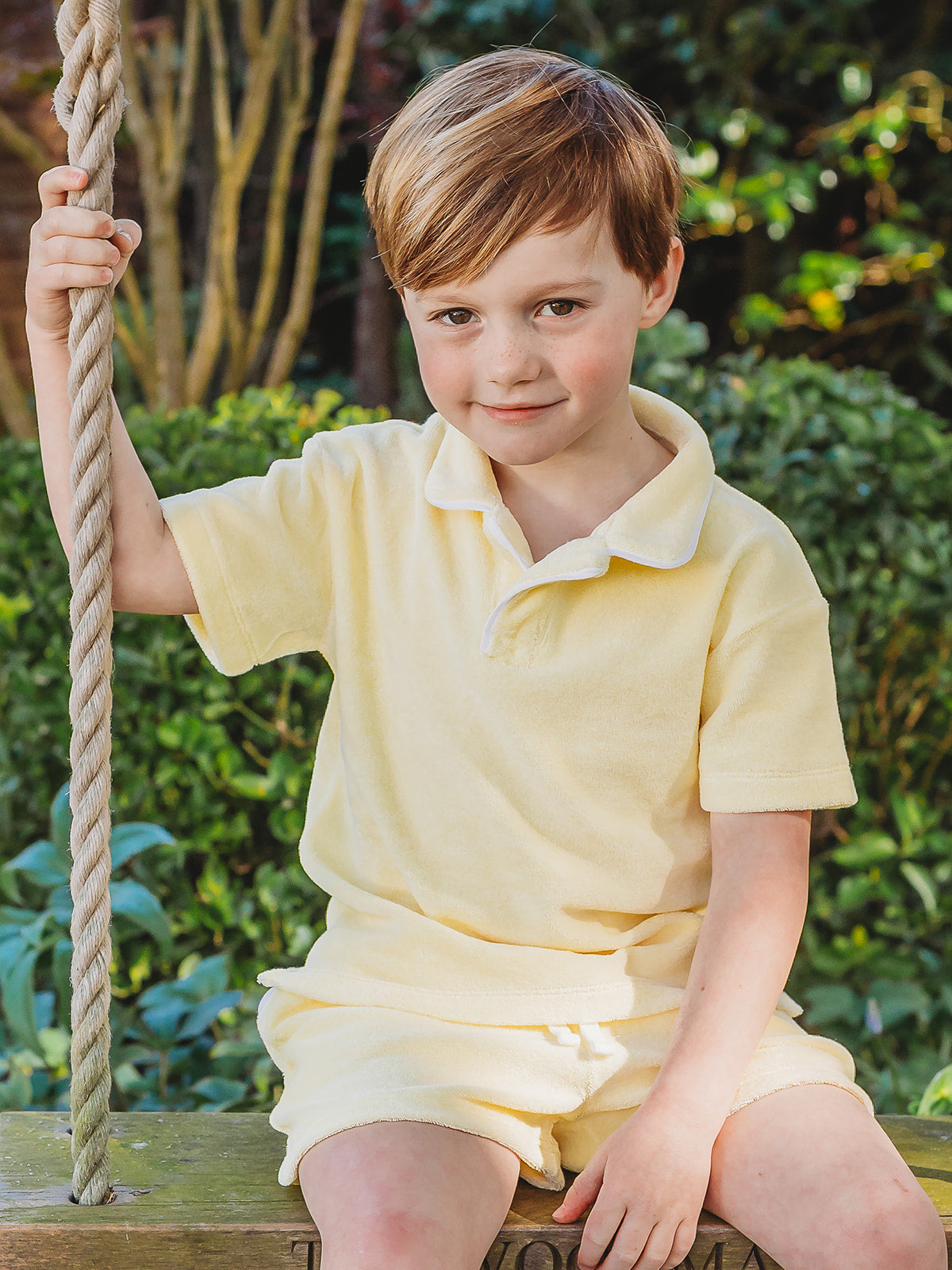 Lemon towelling polo shirt and drawstring shorts, seated on swing