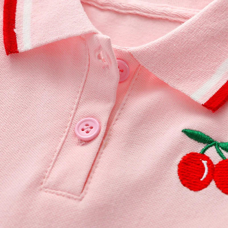 Soft pink polo dress with red-trim collar, button placket, and cherry appliqué